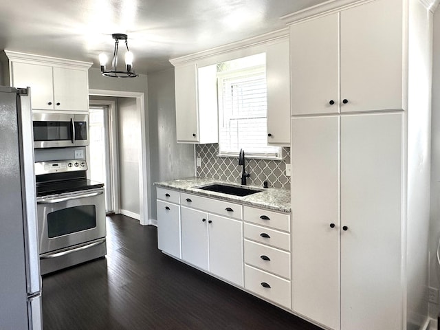 kitchen featuring stainless steel appliances, a sink, white cabinetry, decorative backsplash, and dark wood-style floors