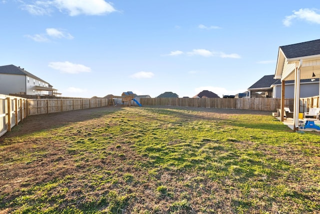 view of yard with a fenced backyard and a playground