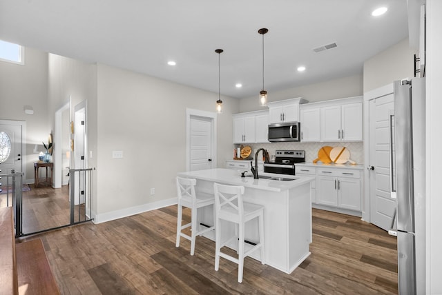 kitchen featuring dark wood finished floors, decorative backsplash, stainless steel appliances, and a sink