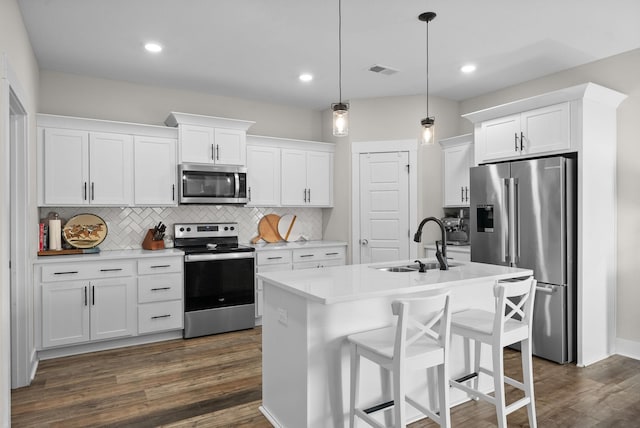 kitchen featuring visible vents, dark wood finished floors, stainless steel appliances, white cabinetry, and a sink