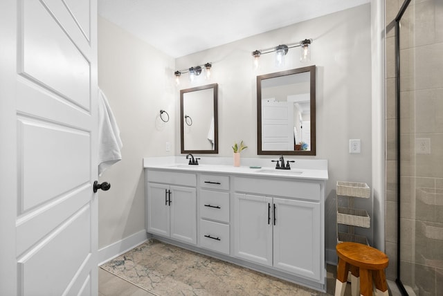 bathroom with double vanity, baseboards, a tile shower, and a sink