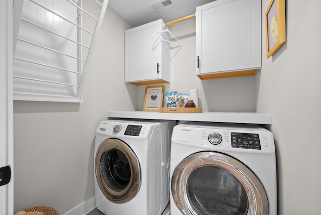 laundry room with cabinet space, baseboards, visible vents, and washing machine and clothes dryer