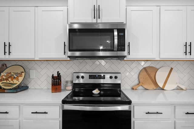 kitchen with electric range, stainless steel microwave, decorative backsplash, and white cabinets