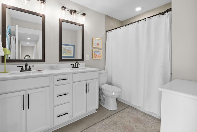 bathroom with toilet, a shower with curtain, double vanity, and a sink