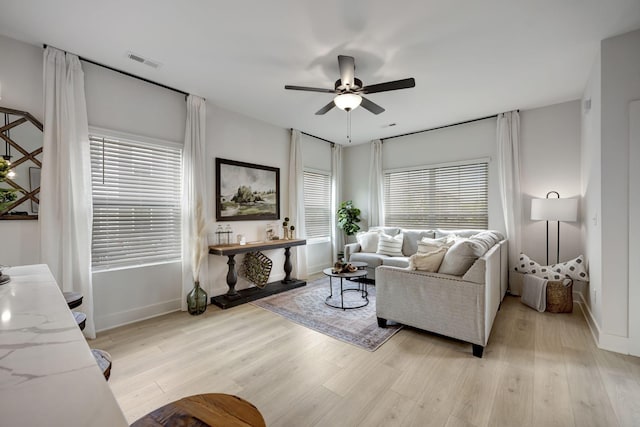 living area featuring ceiling fan, a wealth of natural light, light wood-type flooring, and visible vents