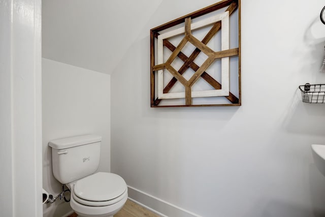 bathroom featuring baseboards, vaulted ceiling, toilet, and wood finished floors