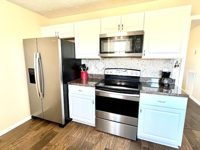 kitchen with a textured ceiling, white cabinetry, appliances with stainless steel finishes, decorative backsplash, and dark wood finished floors