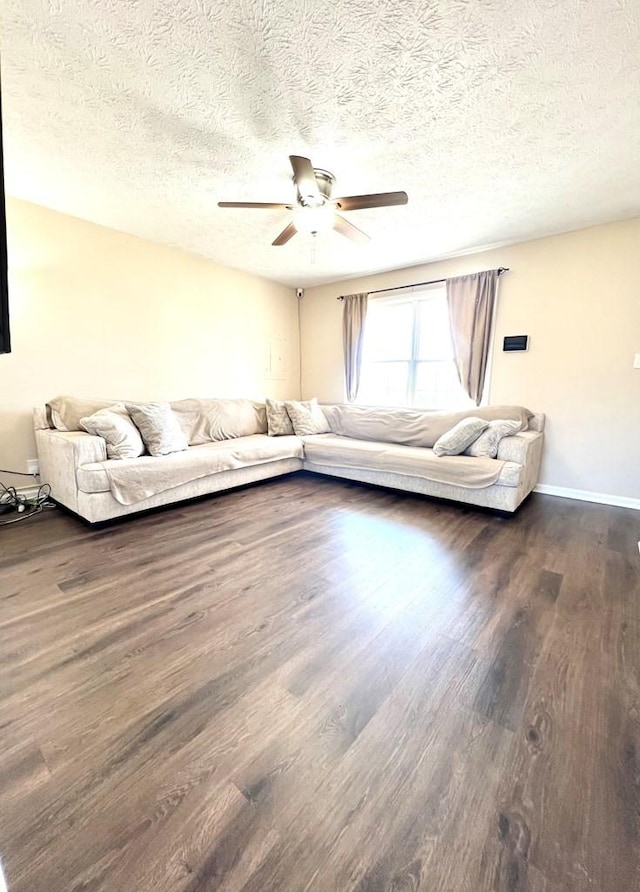 unfurnished living room featuring a textured ceiling, dark wood finished floors, a ceiling fan, and baseboards