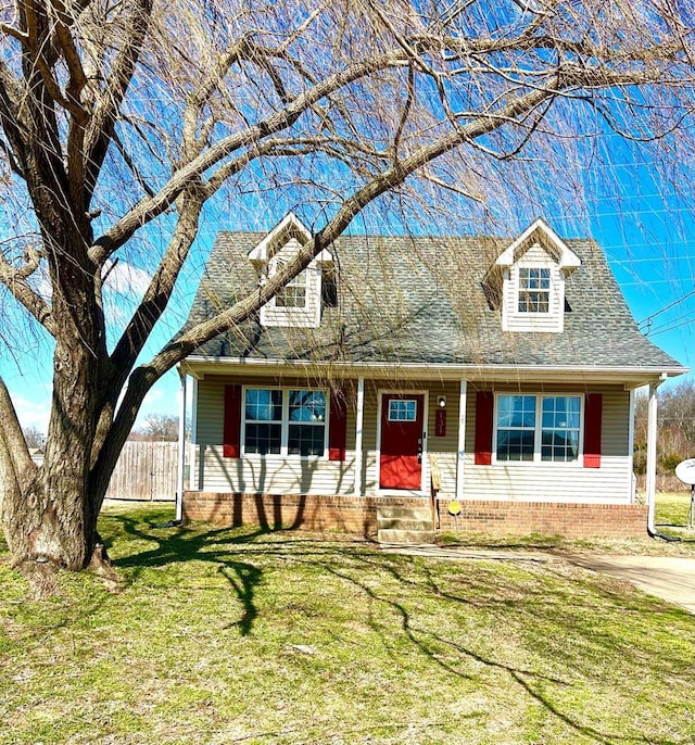 cape cod home featuring a shingled roof, a front yard, and fence