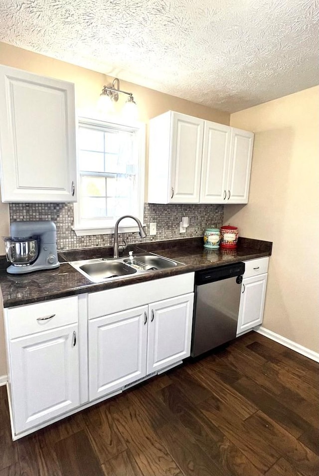 kitchen featuring dark wood-style floors, dark countertops, backsplash, stainless steel dishwasher, and a sink