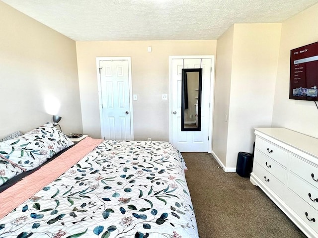 bedroom with baseboards, dark carpet, and a textured ceiling