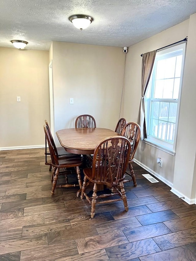 dining room featuring visible vents, a textured ceiling, baseboards, and wood finished floors