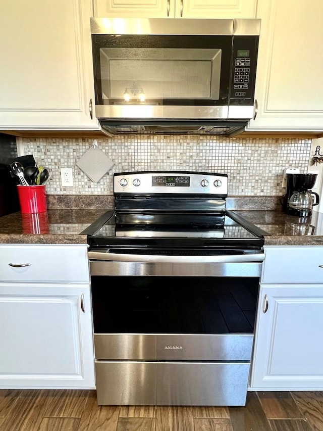 kitchen with stainless steel appliances, dark countertops, decorative backsplash, and dark wood-style floors