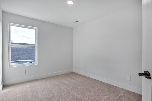 carpeted spare room featuring visible vents and baseboards