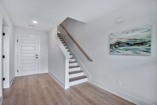 foyer featuring stairway, light wood-type flooring, visible vents, and baseboards