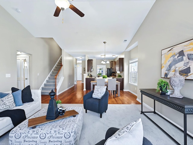 living room with lofted ceiling, stairway, a ceiling fan, wood finished floors, and baseboards