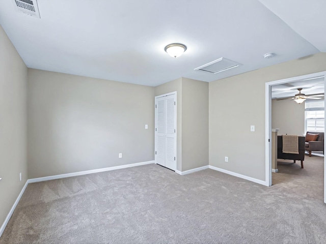 unfurnished room with visible vents, carpet, attic access, and baseboards