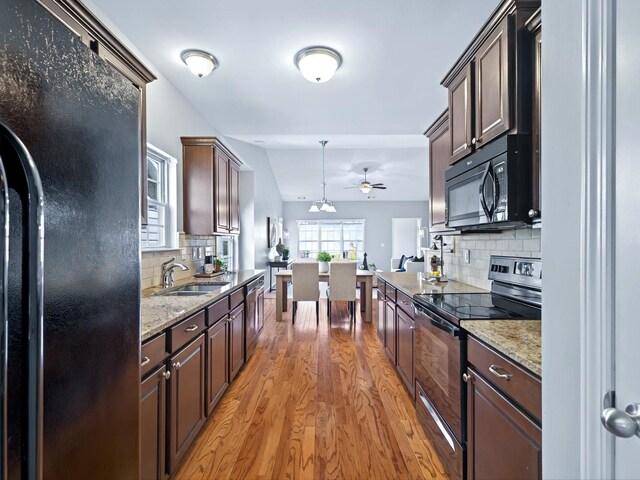 kitchen with black appliances, dark brown cabinets, a sink, and light wood-style floors