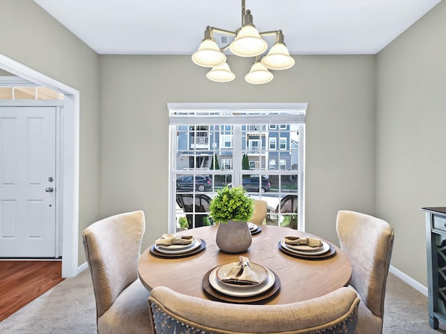 carpeted dining space with baseboards and an inviting chandelier
