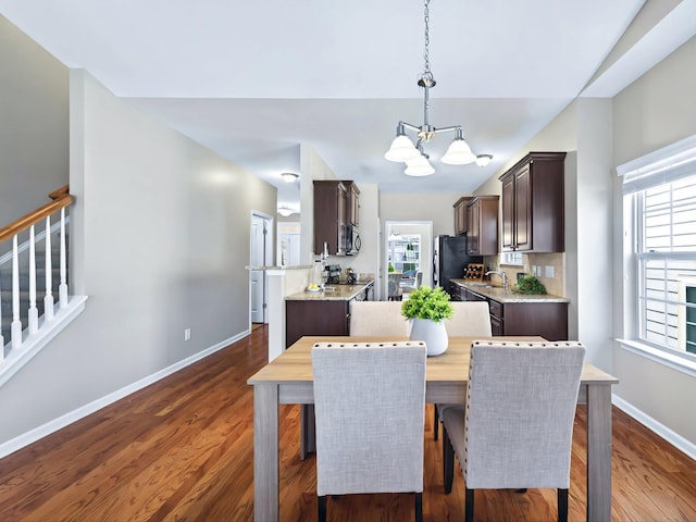 dining room with a wealth of natural light, dark wood-style flooring, baseboards, and stairs