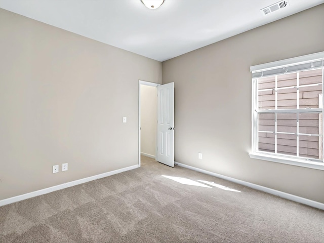 carpeted spare room with visible vents and baseboards