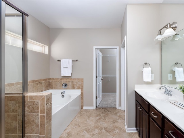full bathroom featuring tile patterned flooring, a garden tub, vanity, a stall shower, and a walk in closet
