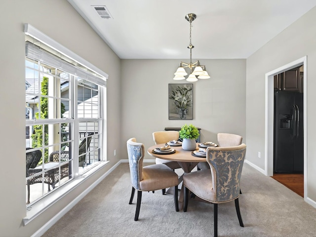 carpeted dining area with baseboards, visible vents, and a notable chandelier