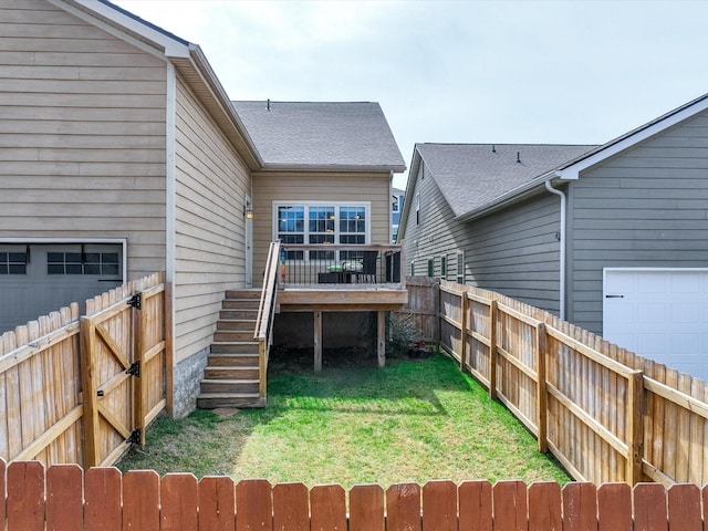 back of property with a garage, a lawn, a fenced backyard, stairs, and a wooden deck