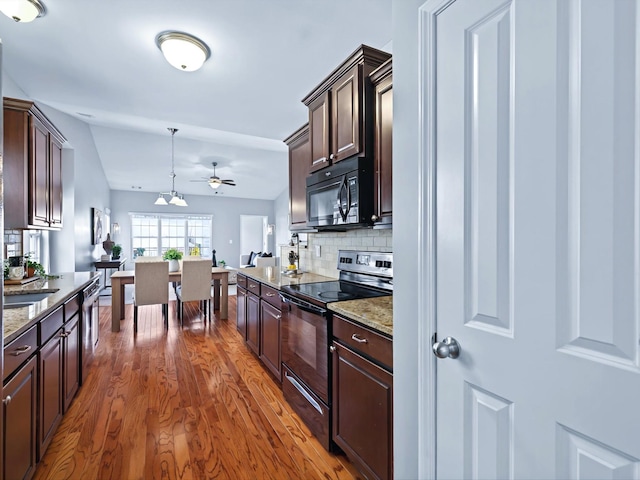 kitchen featuring dark brown cabinetry, hanging light fixtures, black appliances, tasteful backsplash, and dark wood finished floors