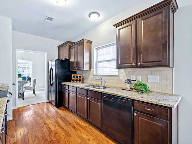 kitchen with decorative backsplash, light wood-style flooring, dark brown cabinets, black appliances, and a sink