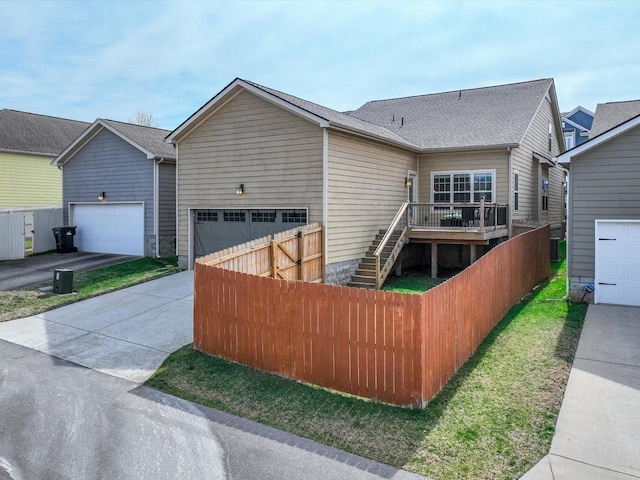 view of front of house with a shingled roof, driveway, fence, and stairway