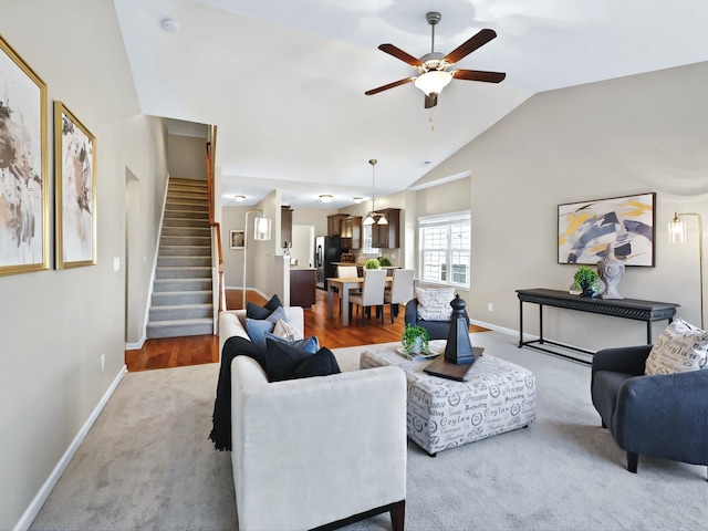 carpeted living area with a ceiling fan, lofted ceiling, stairway, and baseboards