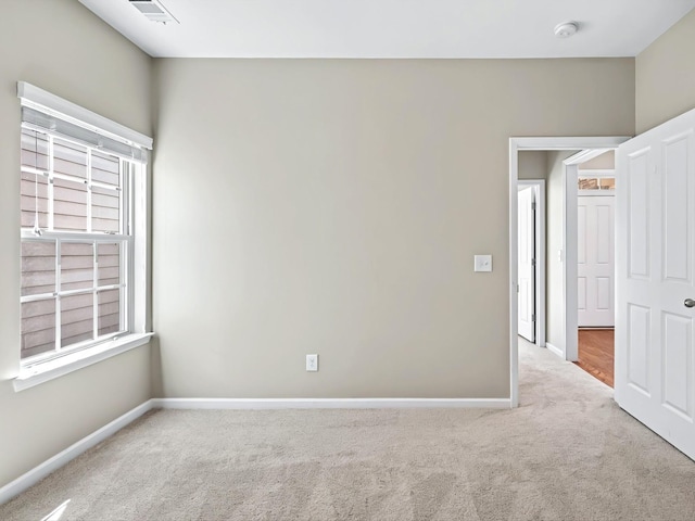 carpeted empty room with visible vents and baseboards