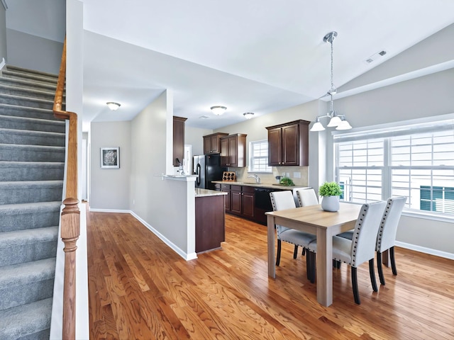 dining space featuring an inviting chandelier, light wood-style flooring, stairs, and visible vents
