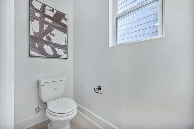 bathroom with toilet, baseboards, and wood finished floors