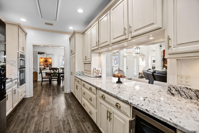 kitchen with dark wood-style floors, wine cooler, visible vents, cream cabinets, and ornamental molding