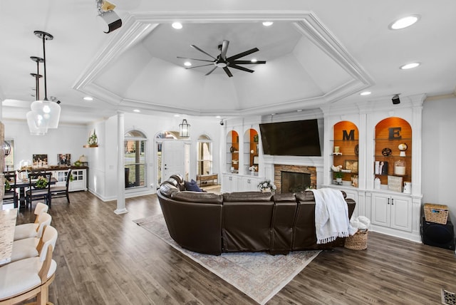 living room with decorative columns, a fireplace, a tray ceiling, and wood finished floors