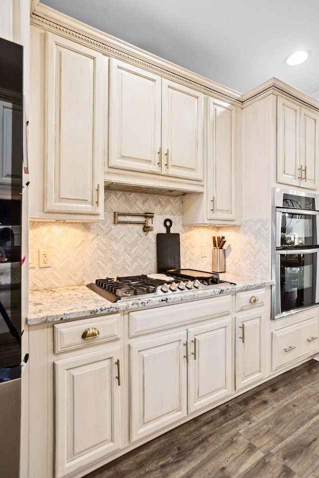 kitchen with stainless steel appliances, dark wood-type flooring, and cream cabinets