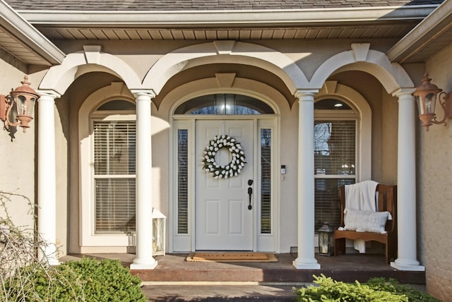 property entrance with a shingled roof, a porch, and stucco siding