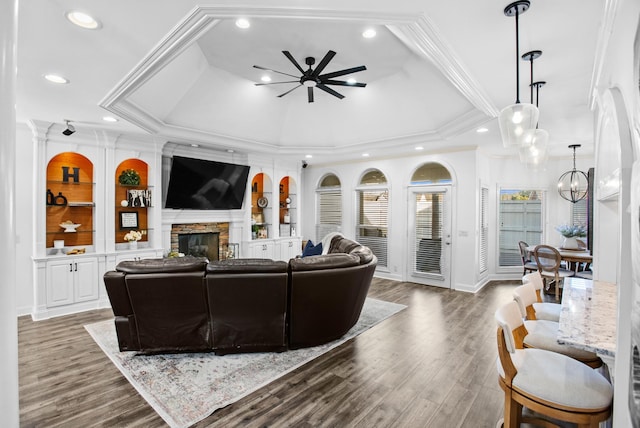 living area with built in features, crown molding, a fireplace, recessed lighting, and wood finished floors