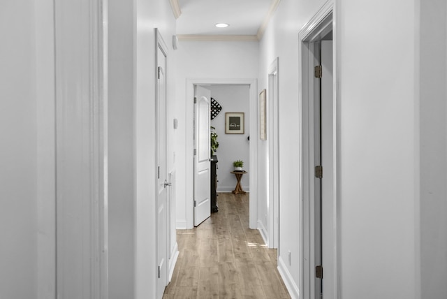 hall with light wood-style flooring, baseboards, and ornamental molding