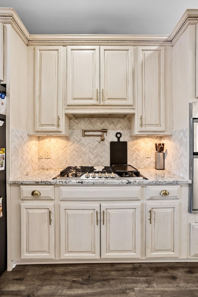 kitchen featuring stainless steel gas cooktop, cream cabinetry, light stone counters, and tasteful backsplash