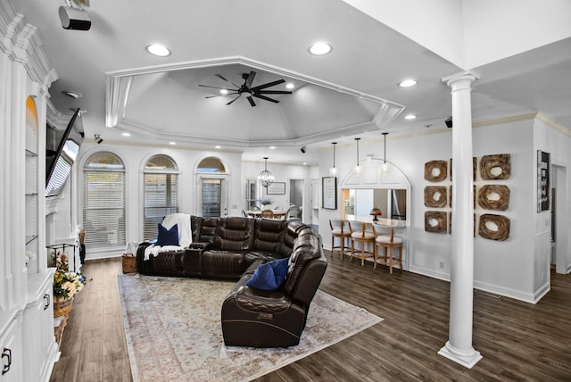 living area with crown molding, a raised ceiling, a ceiling fan, wood finished floors, and ornate columns