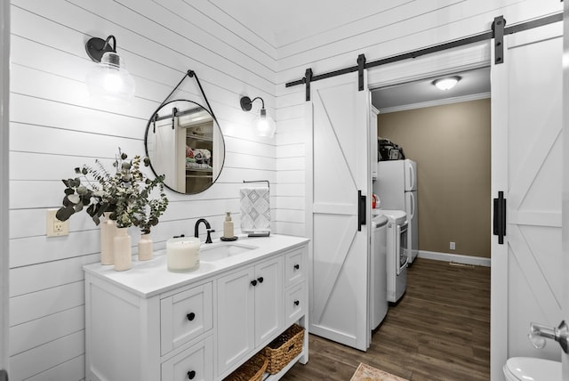 bathroom featuring toilet, ornamental molding, wood finished floors, washer and dryer, and vanity