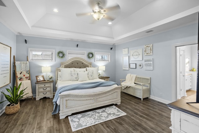 bedroom with dark wood-style floors, a tray ceiling, and baseboards