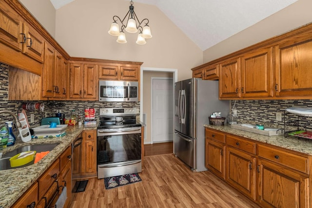 kitchen with lofted ceiling, stainless steel appliances, light wood-type flooring, and brown cabinets