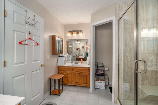 bathroom with a textured ceiling, a shower stall, vanity, and baseboards