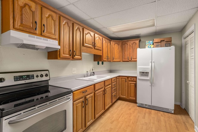 kitchen featuring under cabinet range hood, a sink, electric stove, white fridge with ice dispenser, and light wood finished floors