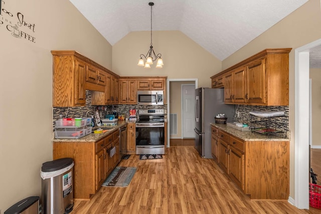 kitchen with stainless steel appliances, lofted ceiling, brown cabinetry, and light wood-style floors