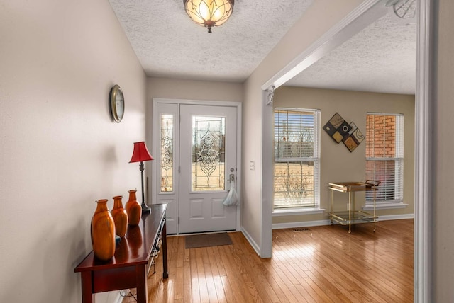 doorway to outside with wood-type flooring, baseboards, and a textured ceiling